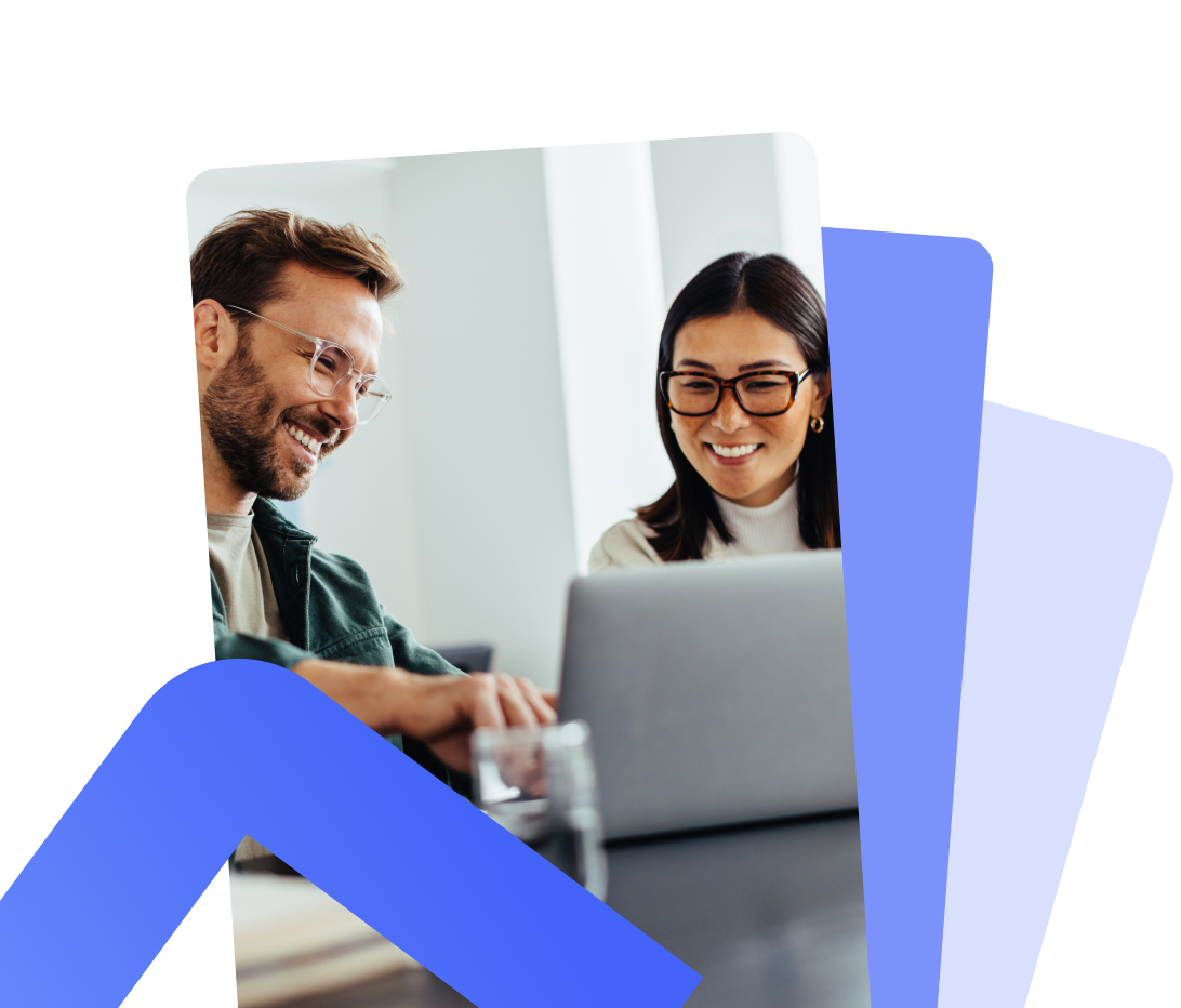 Two colleagues smiling while looking at a laptop together